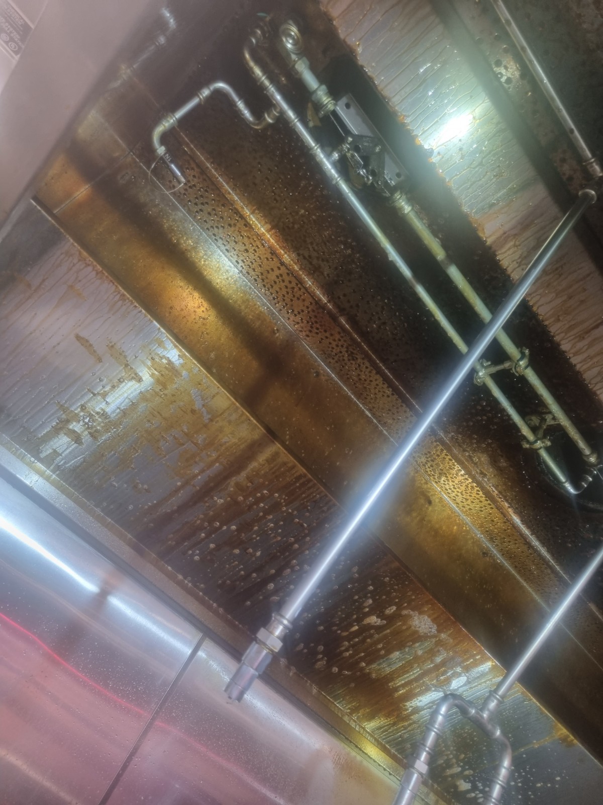Heavy grease build-up on canopy and fire suppression pipes - before cleaning